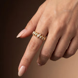 Gold ring with zircons on a finger against a brown background