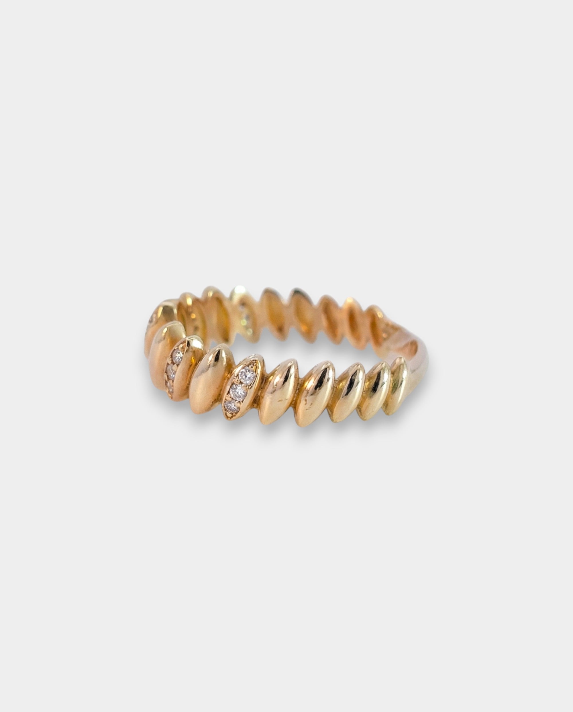 Gold ring with small zircons on a light gray background