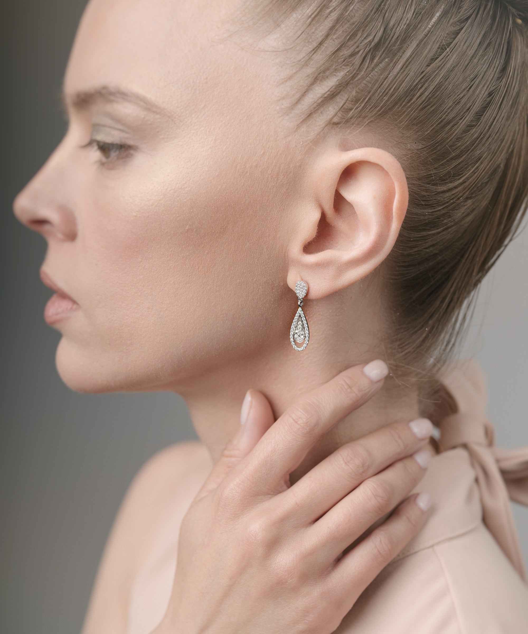 Woman wearing a diamond earring with a neutral background