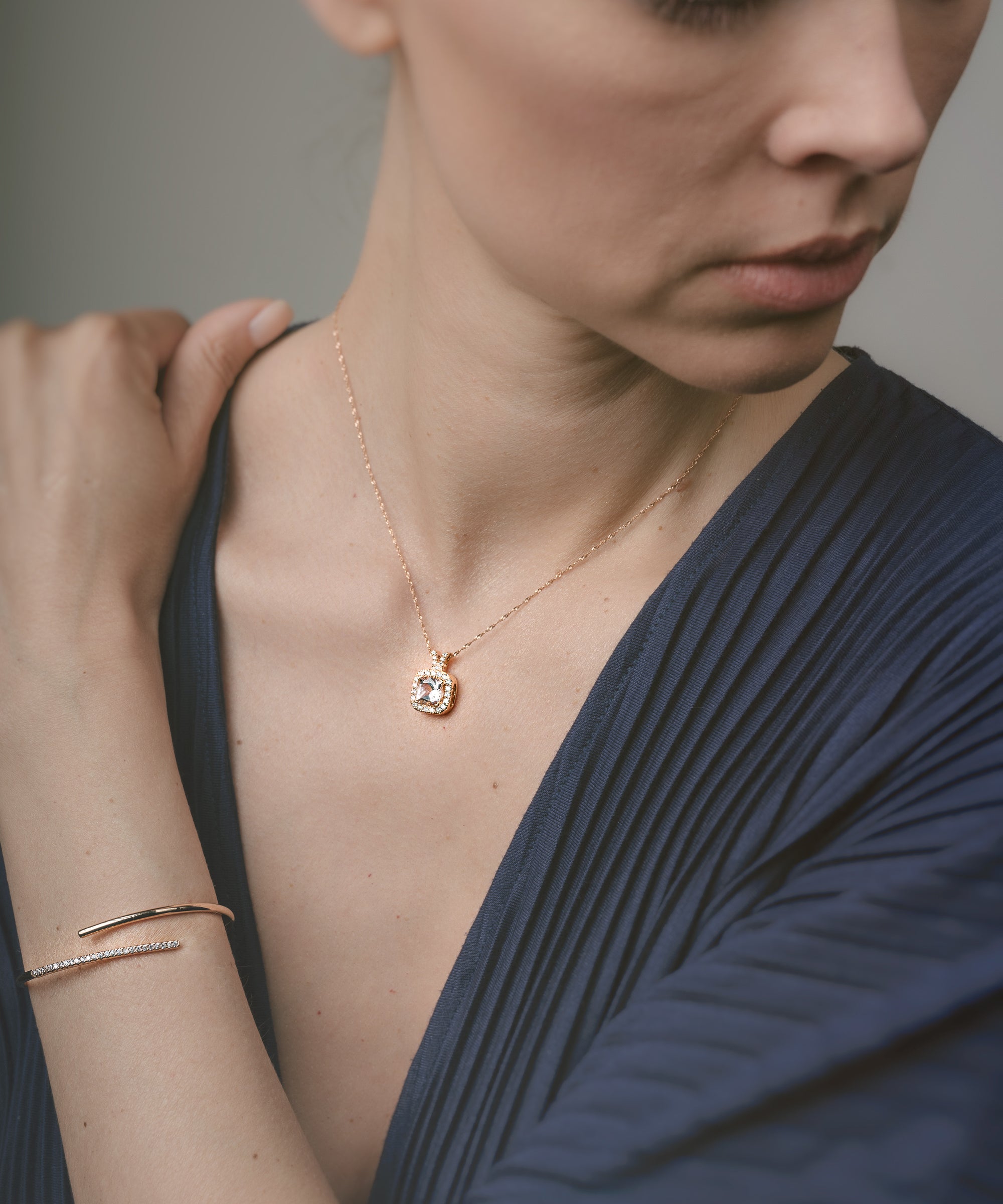 Woman wearing a gold necklace and bracelet against a neutral background
