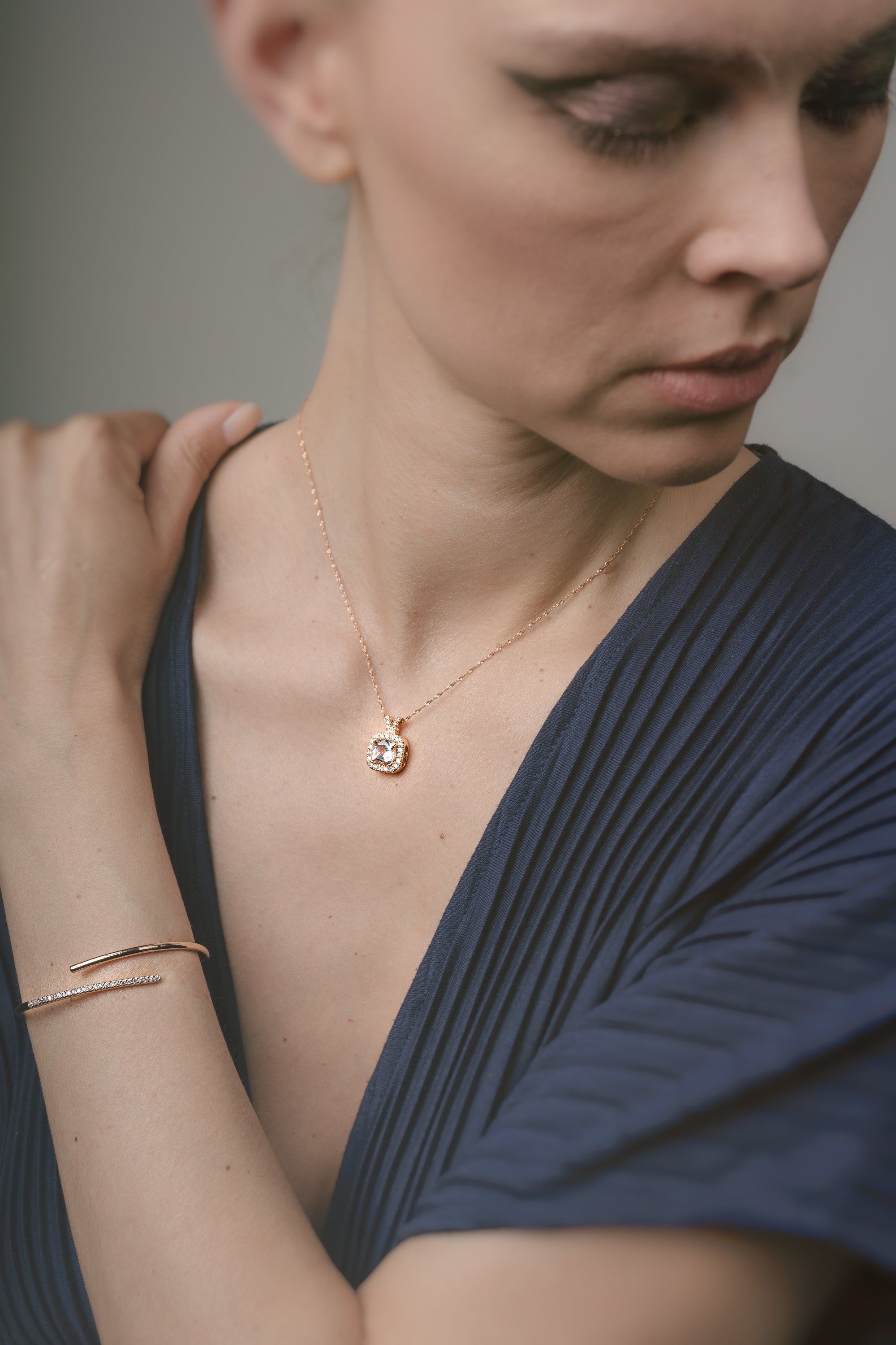 Woman wearing a gold necklace and bracelet against a neutral background