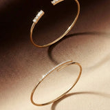 Two gold bangles with embedded stones on a brown surface