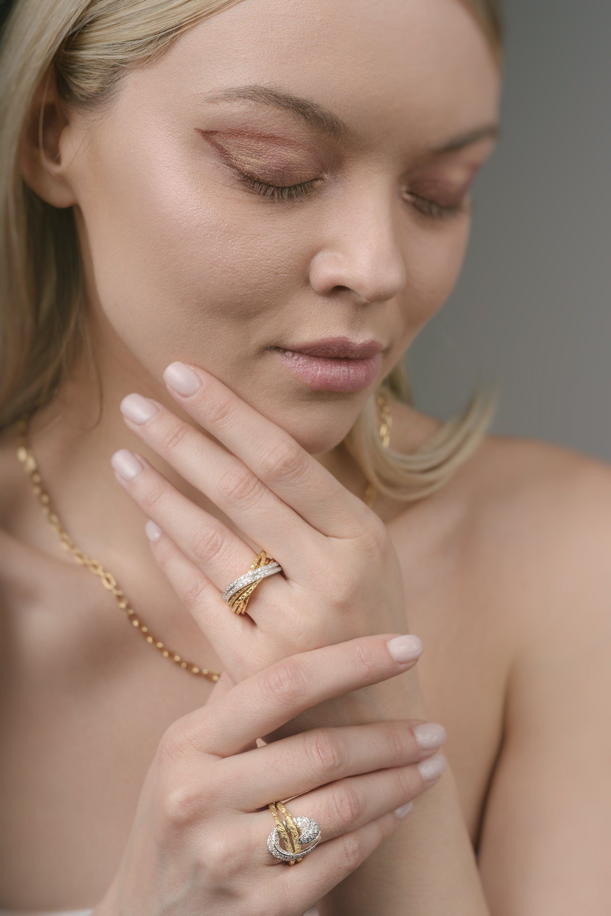 Woman wearing gold jewelry including a necklace, ring, and bracelet.