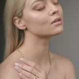 Woman wearing gold jewelry against a neutral background
