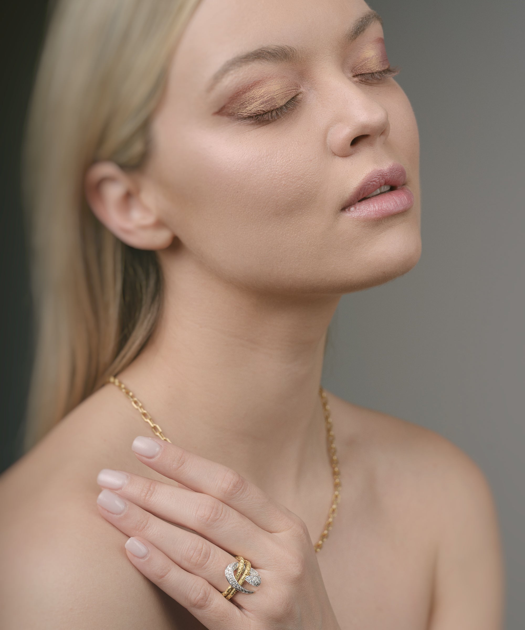 Woman wearing gold jewelry against a neutral background