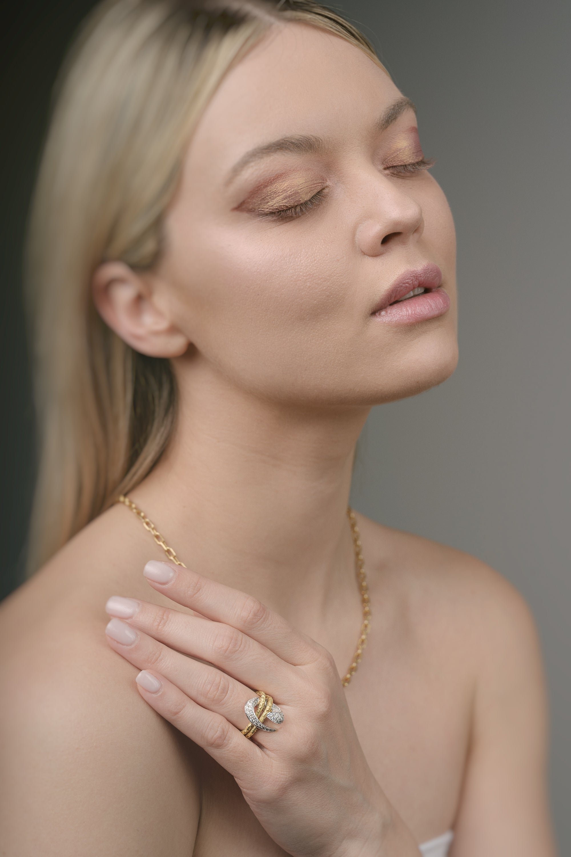 Woman wearing gold jewelry against a neutral background