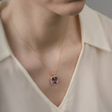 Necklace with a purple amethyst pendant worn by a person in a beige shirt.