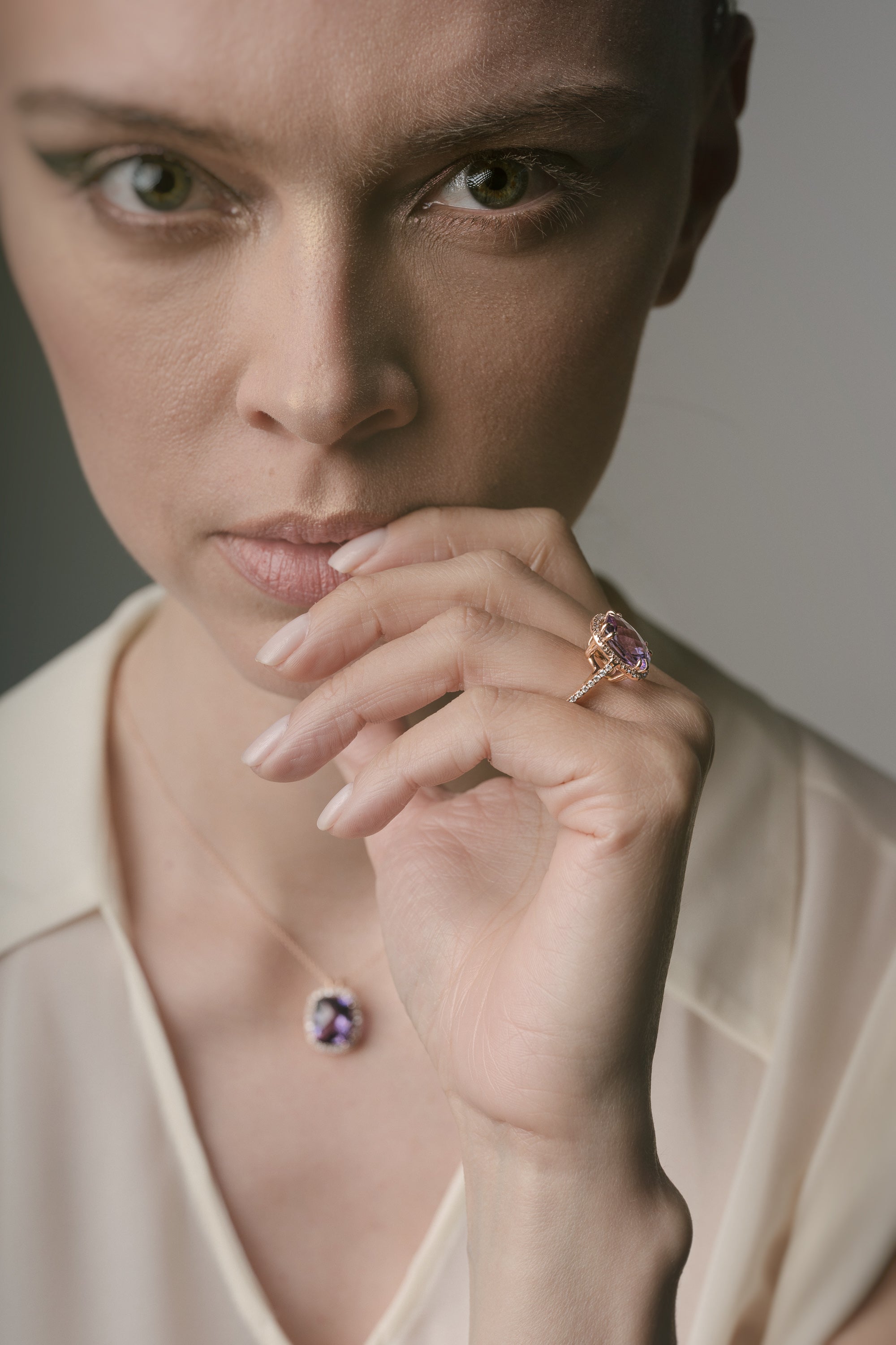 Woman wearing a ring with a purple amethyst against a neutral background