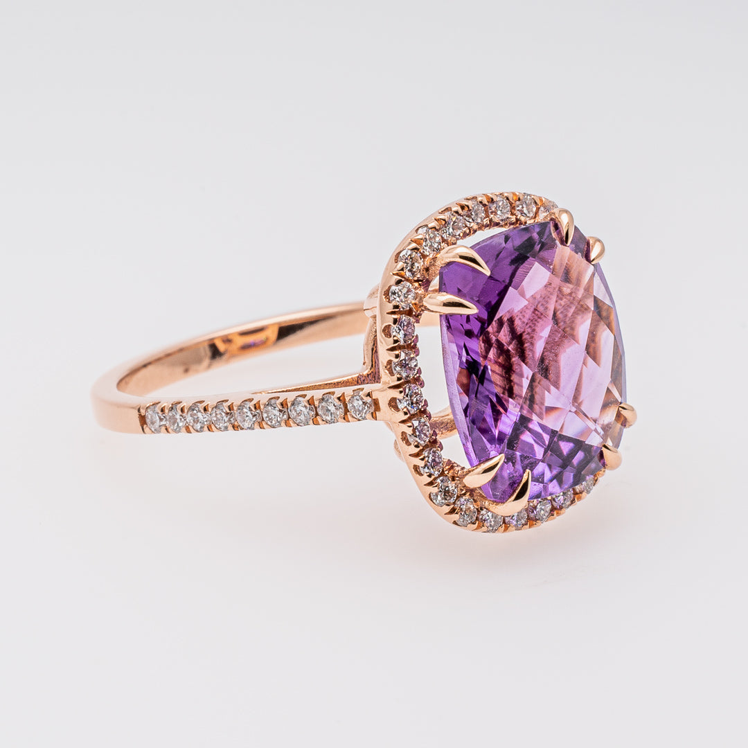 Rose gold ring with a purple amethyst on a light gray background