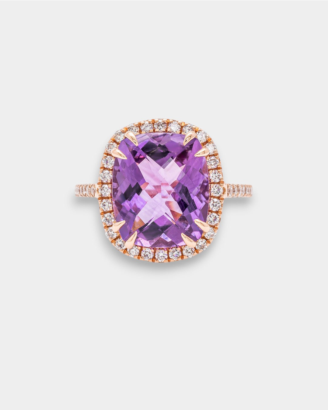 Ring with a purple amethyst and rose gold band on a light gray background