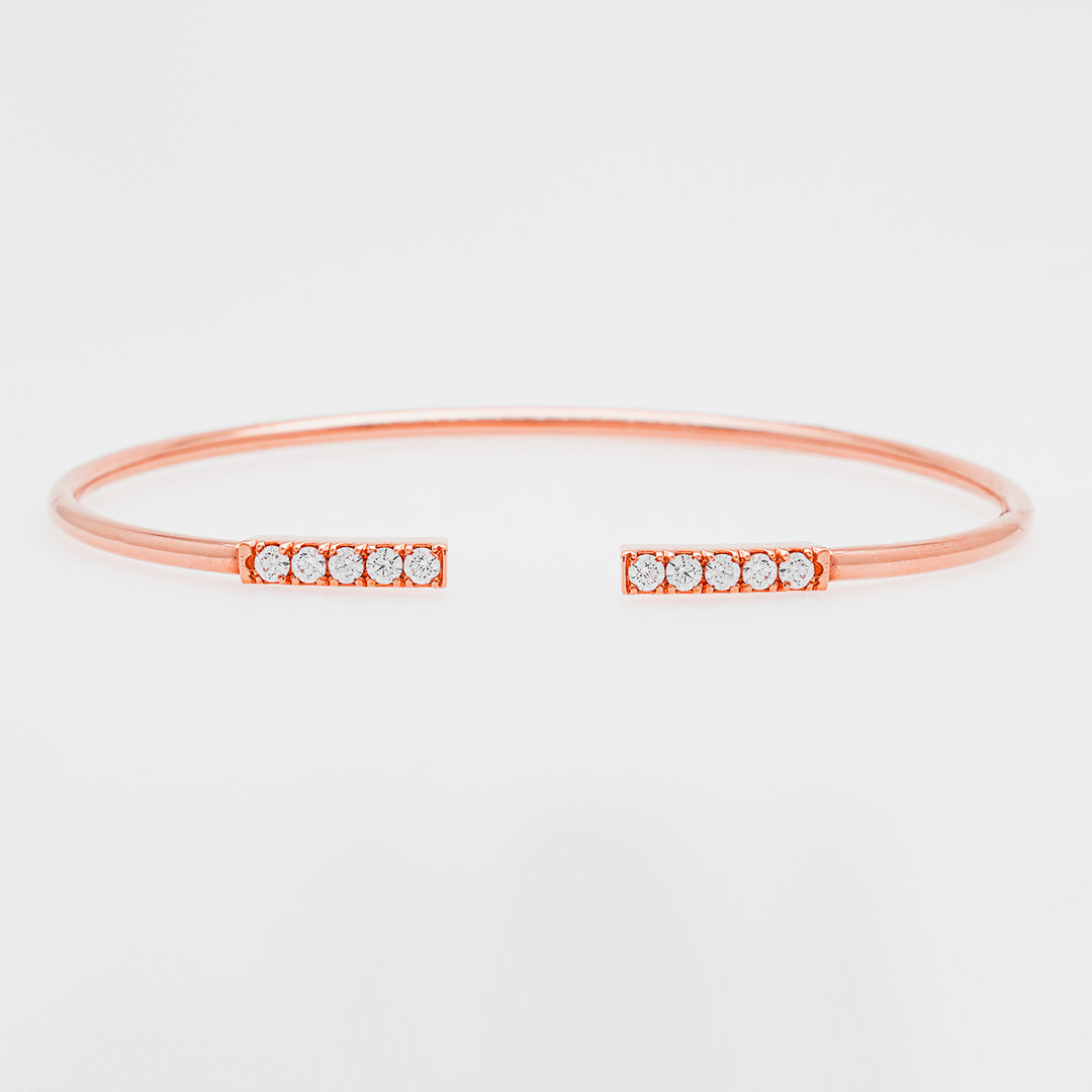 Rose gold bangle with small zircons on a light gray background