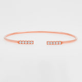 Rose gold bangle with small zircons on a light gray background