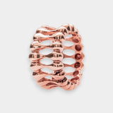 Rose gold ring with a textured design on a light gray background