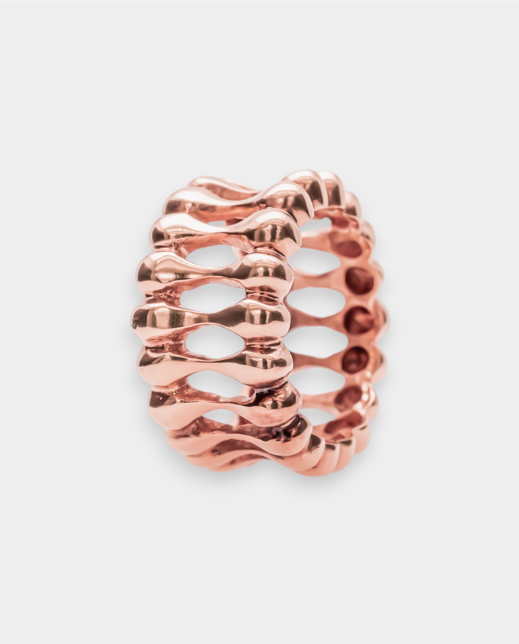 Rose gold ring with a textured design on a light gray background