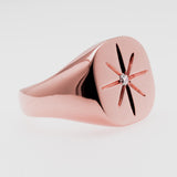 Rose gold ring with star-shaped design on a light gray background