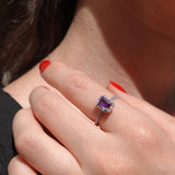 Close-up of a hand wearing an amethyst ring with a blurred background