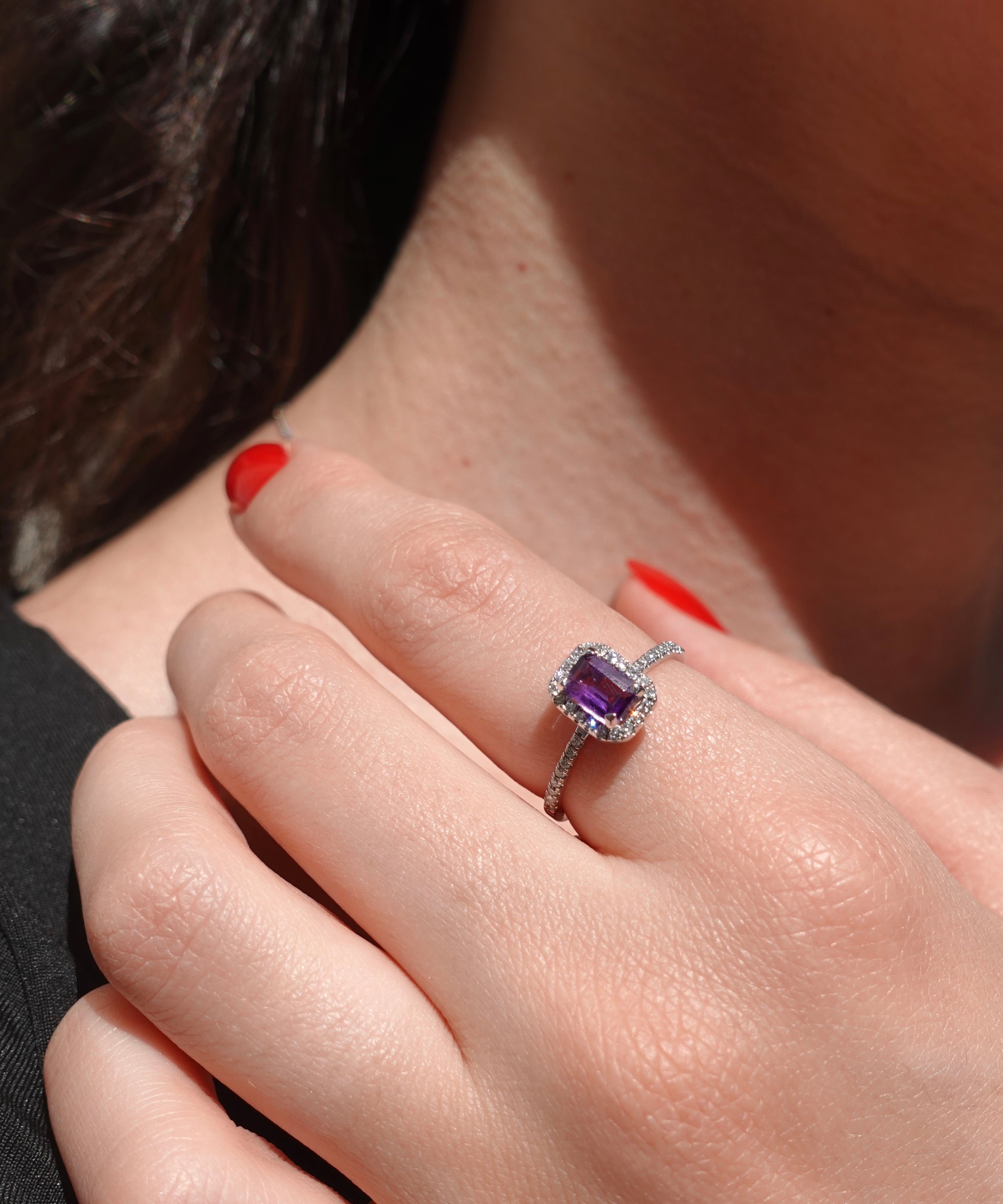 Close-up of a hand wearing an amethyst ring with a blurred background