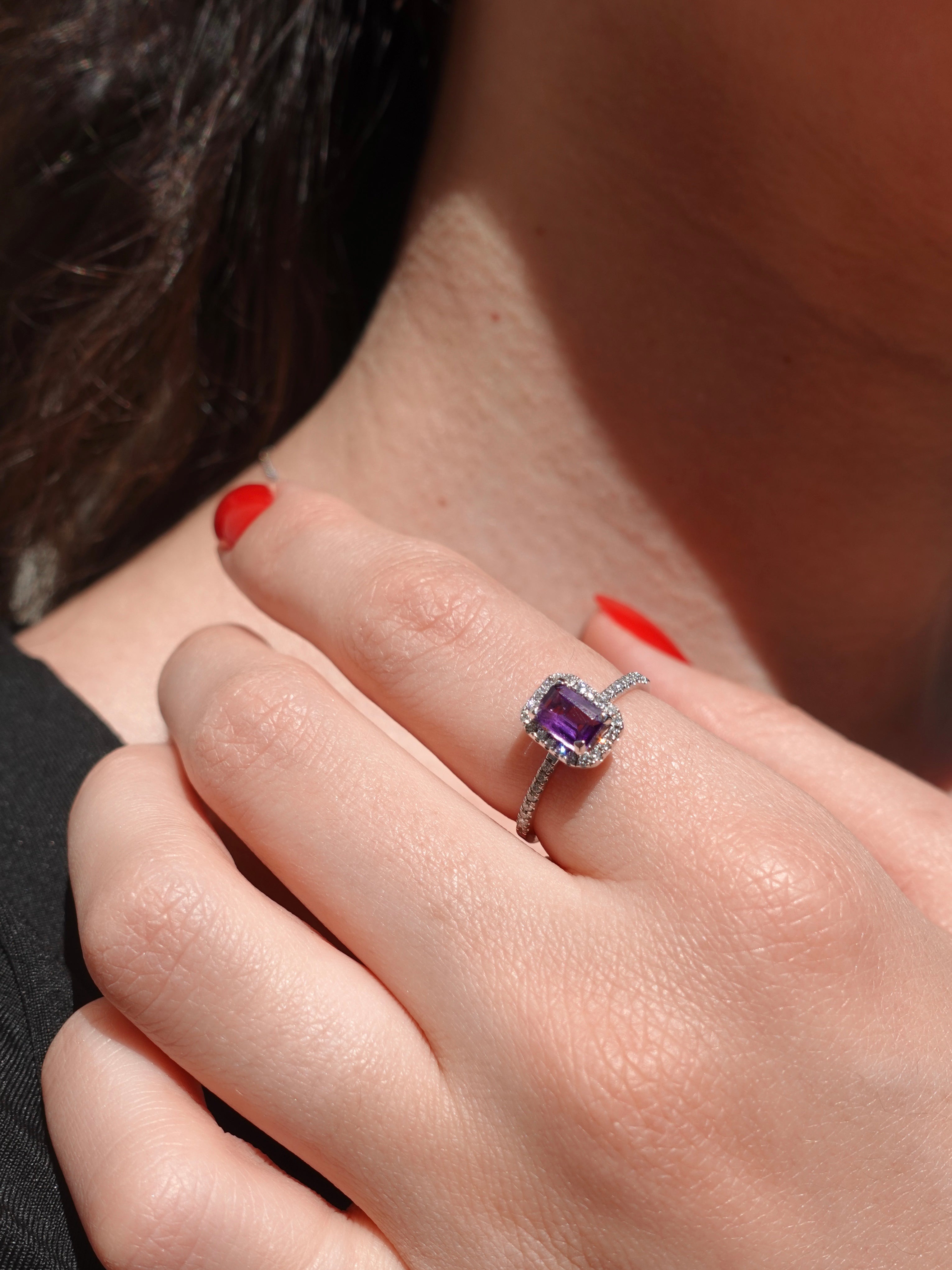 Close-up of a hand wearing an amethyst ring with a blurred background
