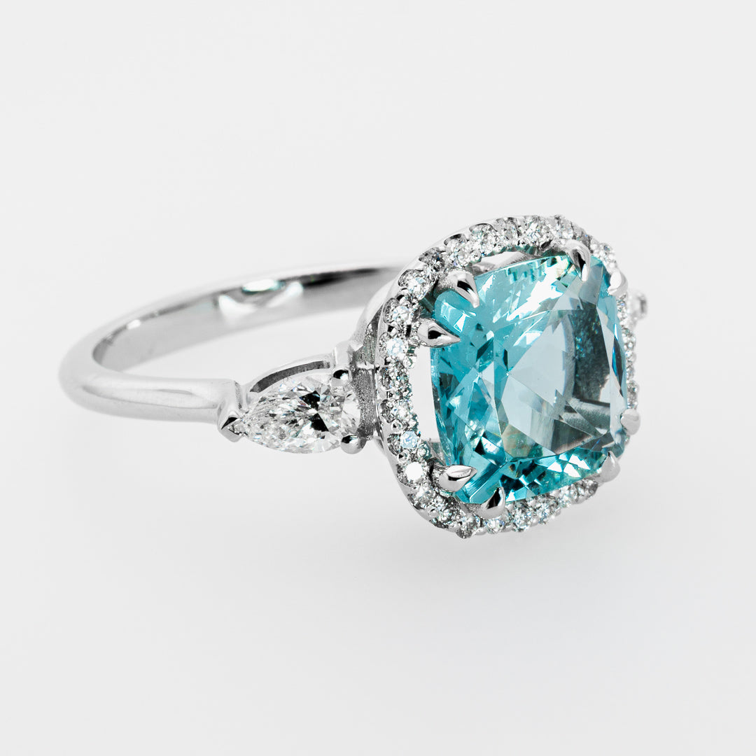 Ring with a blue aquamarine gemstone and white gold setting on a white background