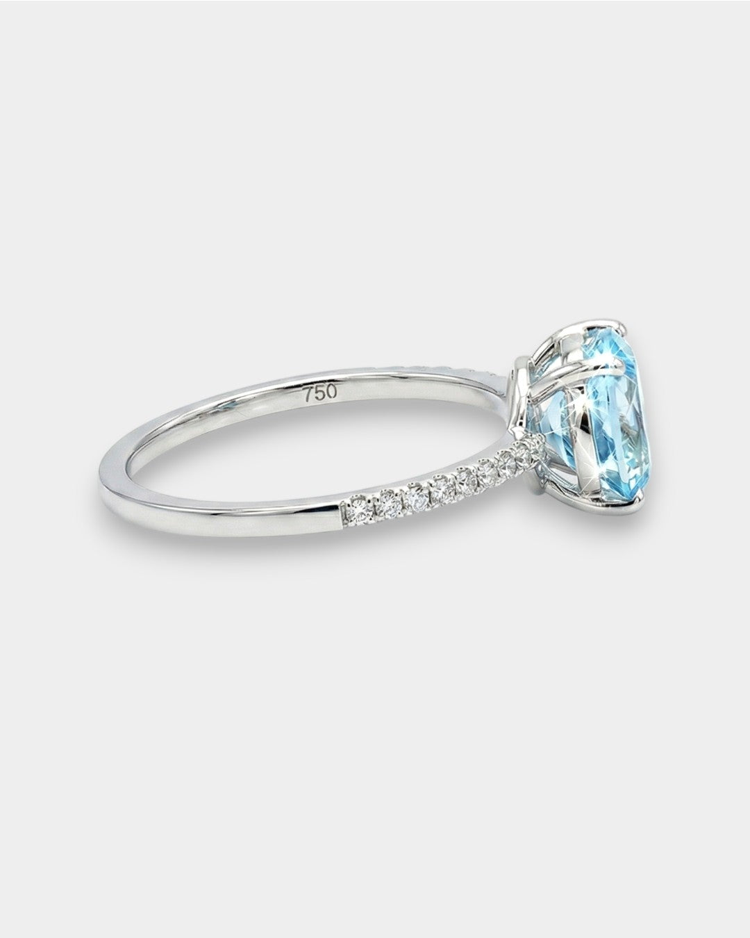 White gold ring with a blue aquamarine and pave diamonds on a white background