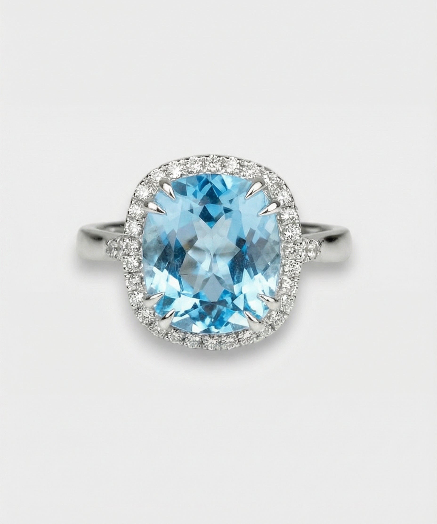 Ring with a blue topaz and diamond-studded halo on a light gray background