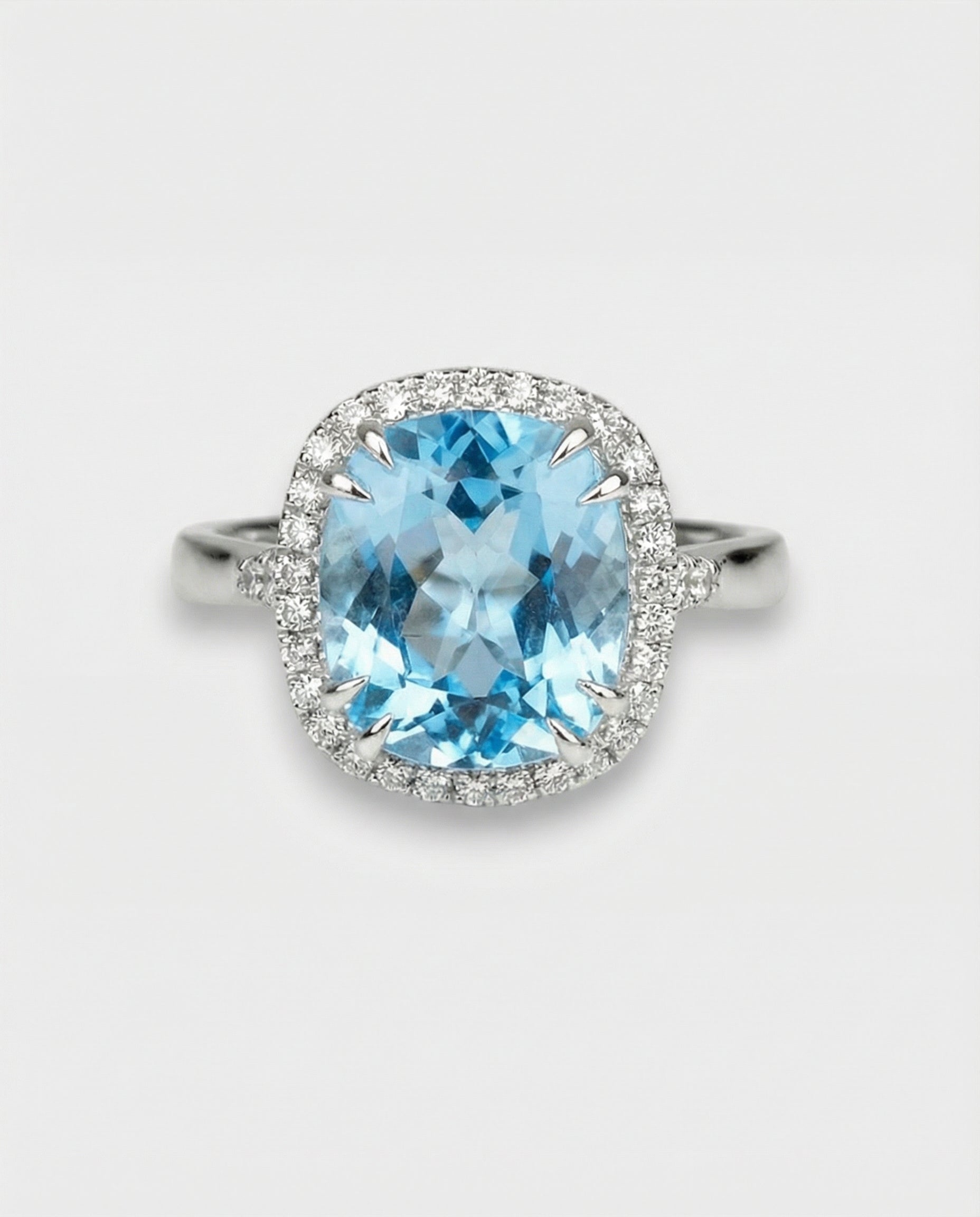 Ring with a blue topaz and diamond-studded halo on a light gray background
