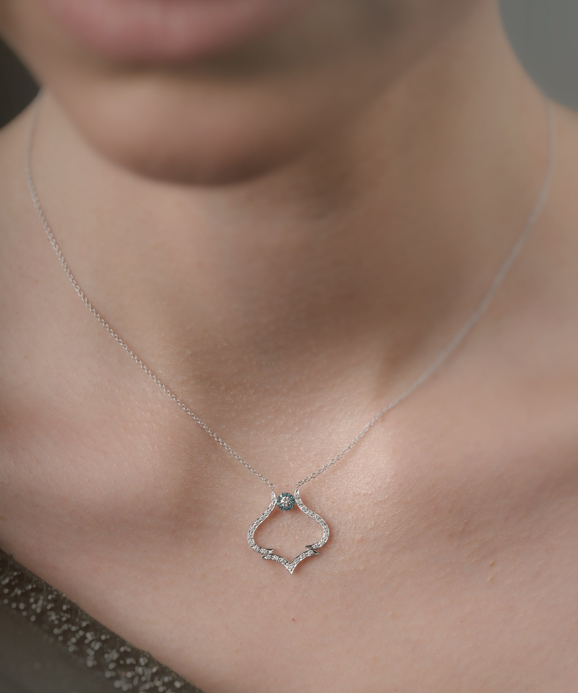 Necklace with a pendant worn by a person, focusing on the jewelry.