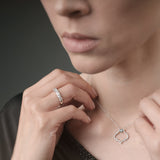 Woman adjusting a delicate necklace with a close-up of the necklace on a neutral background