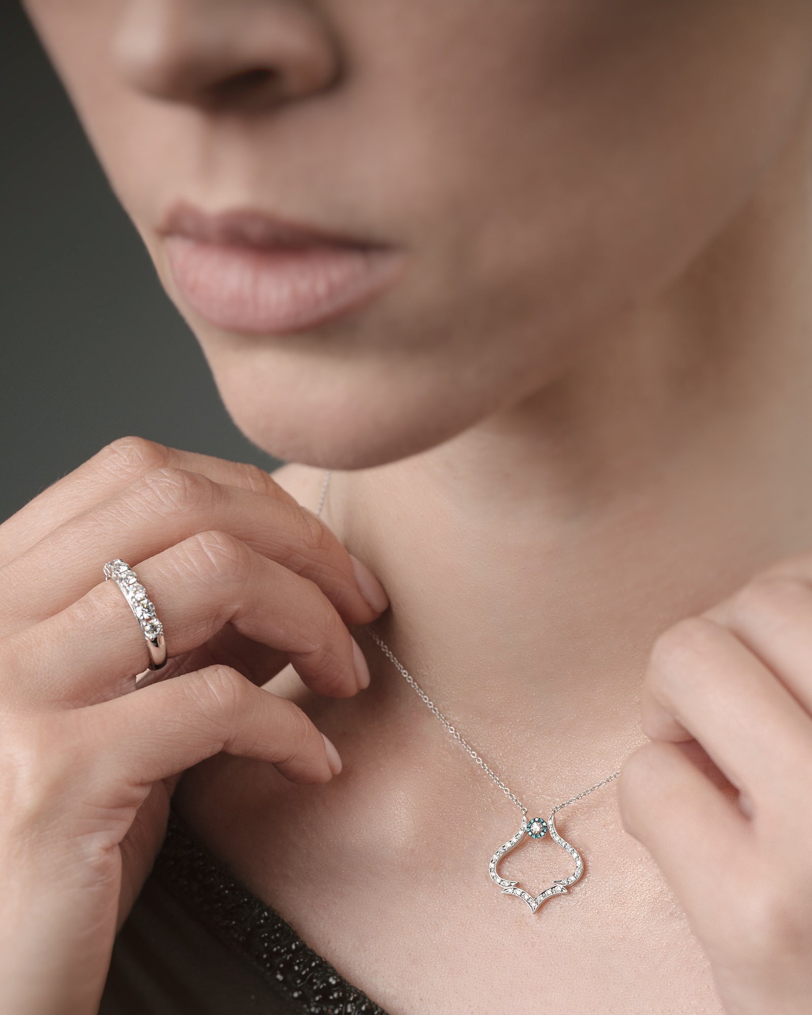 Woman adjusting a delicate necklace with a close-up of the necklace on a neutral background