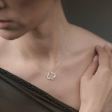 Woman wearing a delicate necklace with a small pendant against a neutral background