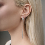 Close-up of a woman wearing a white gold earring with a blurred background