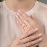 Close-up of a person wearing two rings on their fingers with a neutral background