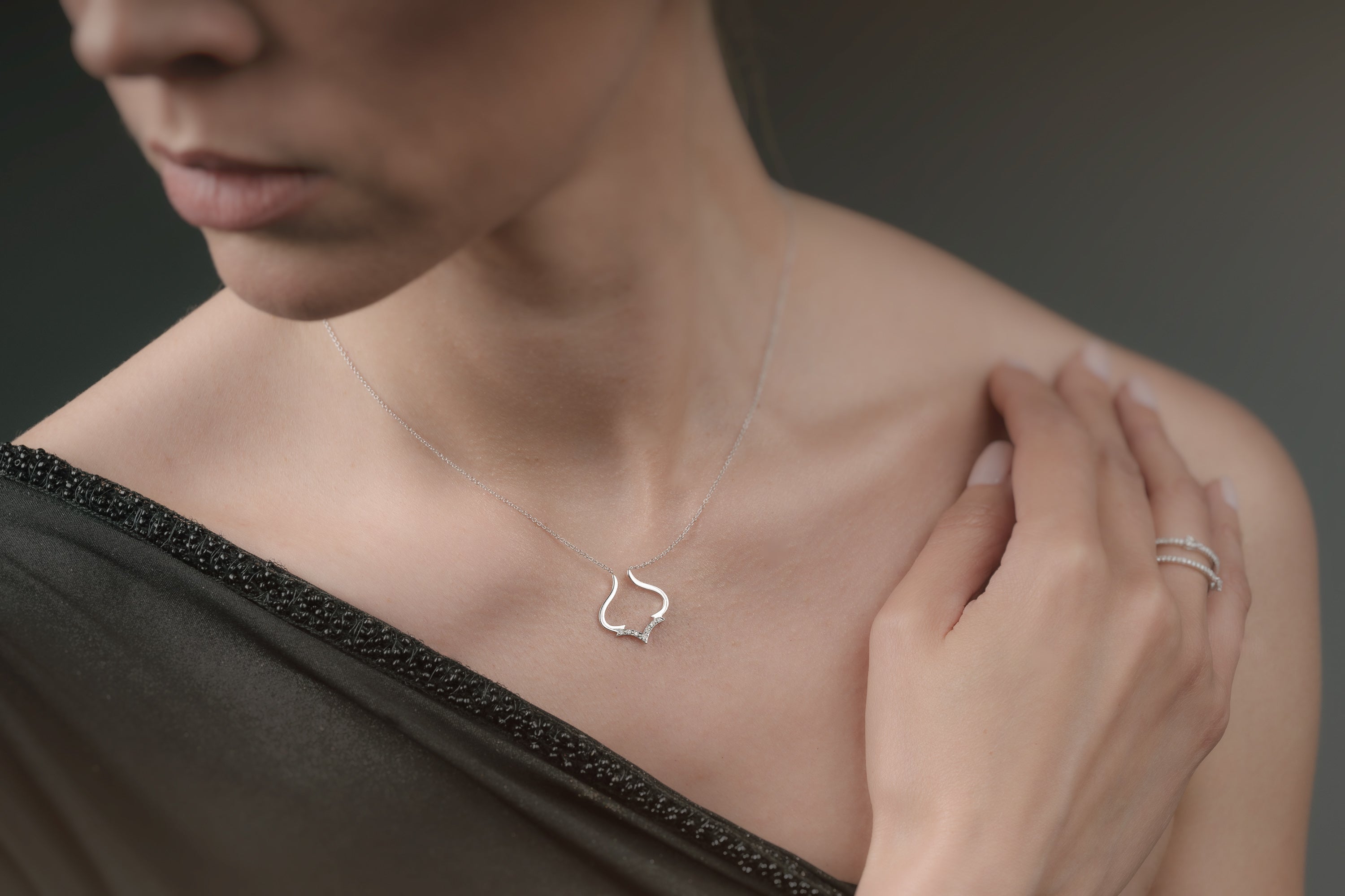Woman wearing a delicate necklace with a small pendant against a neutral background