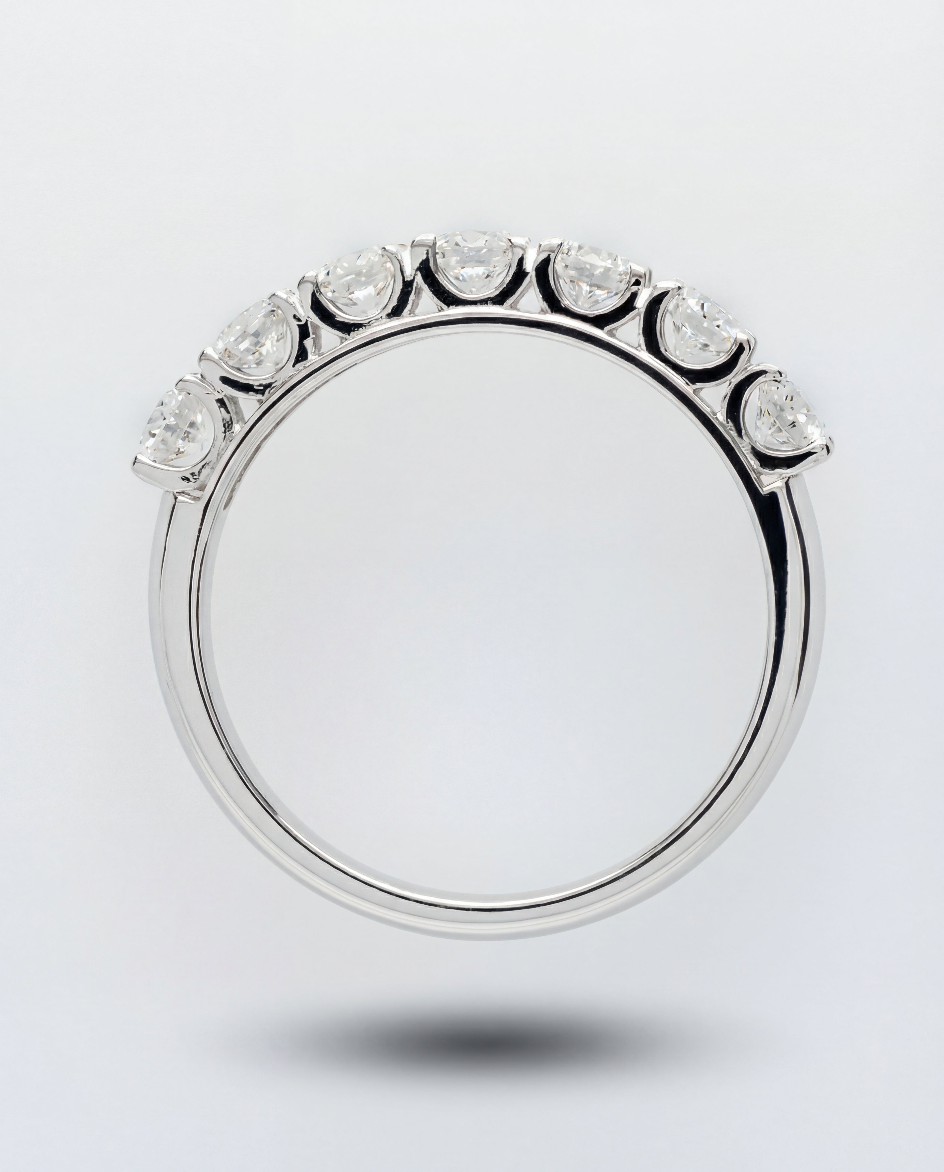 White gold ring with a half diamond band on a light gray background