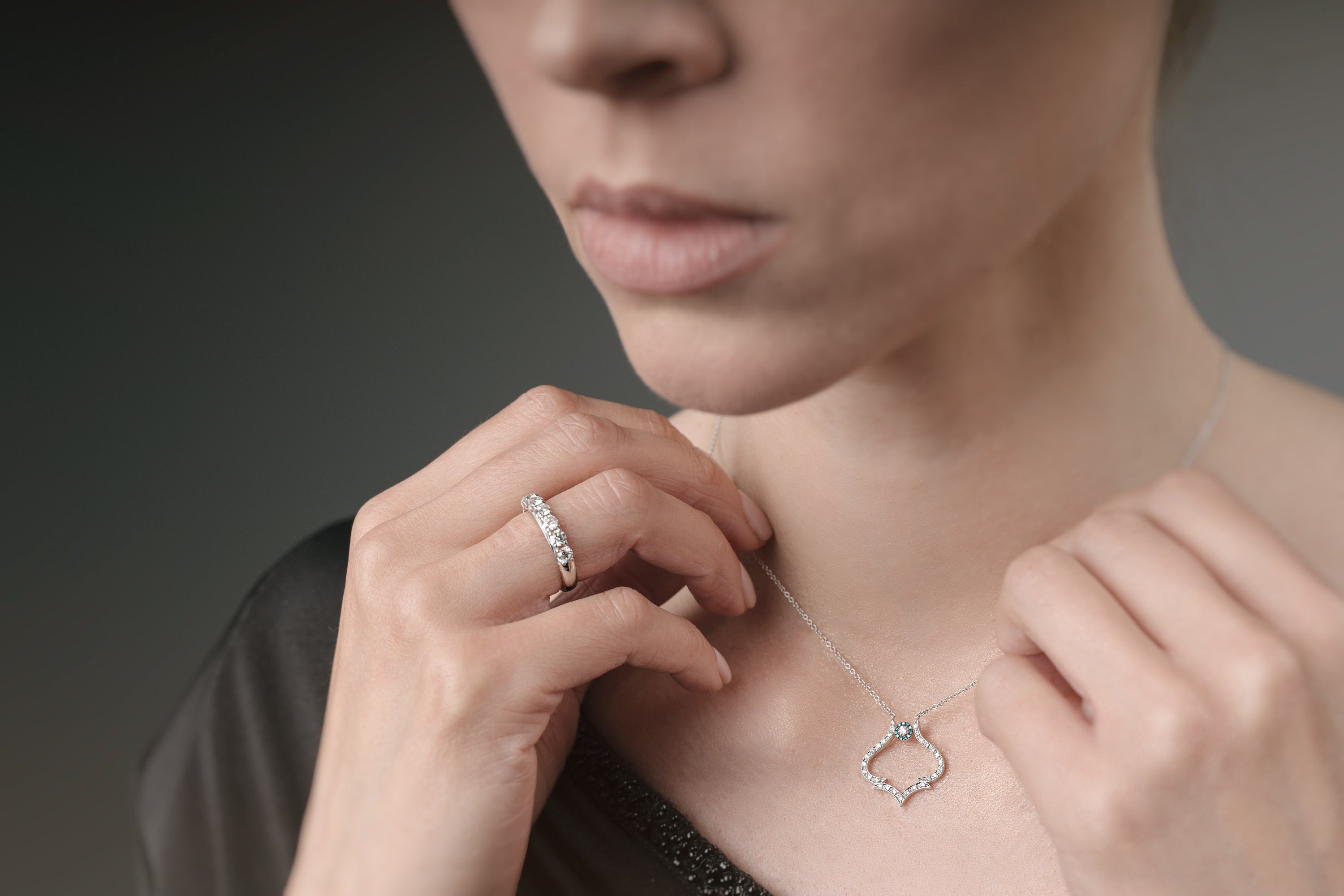 Woman adjusting a delicate necklace with a close-up of her face and hands.