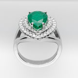 White gold ring with a green emerald gemstone and diamond halo on a light gray background