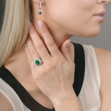 Close-up of a woman wearing emerald green gemstone earrings and ring.