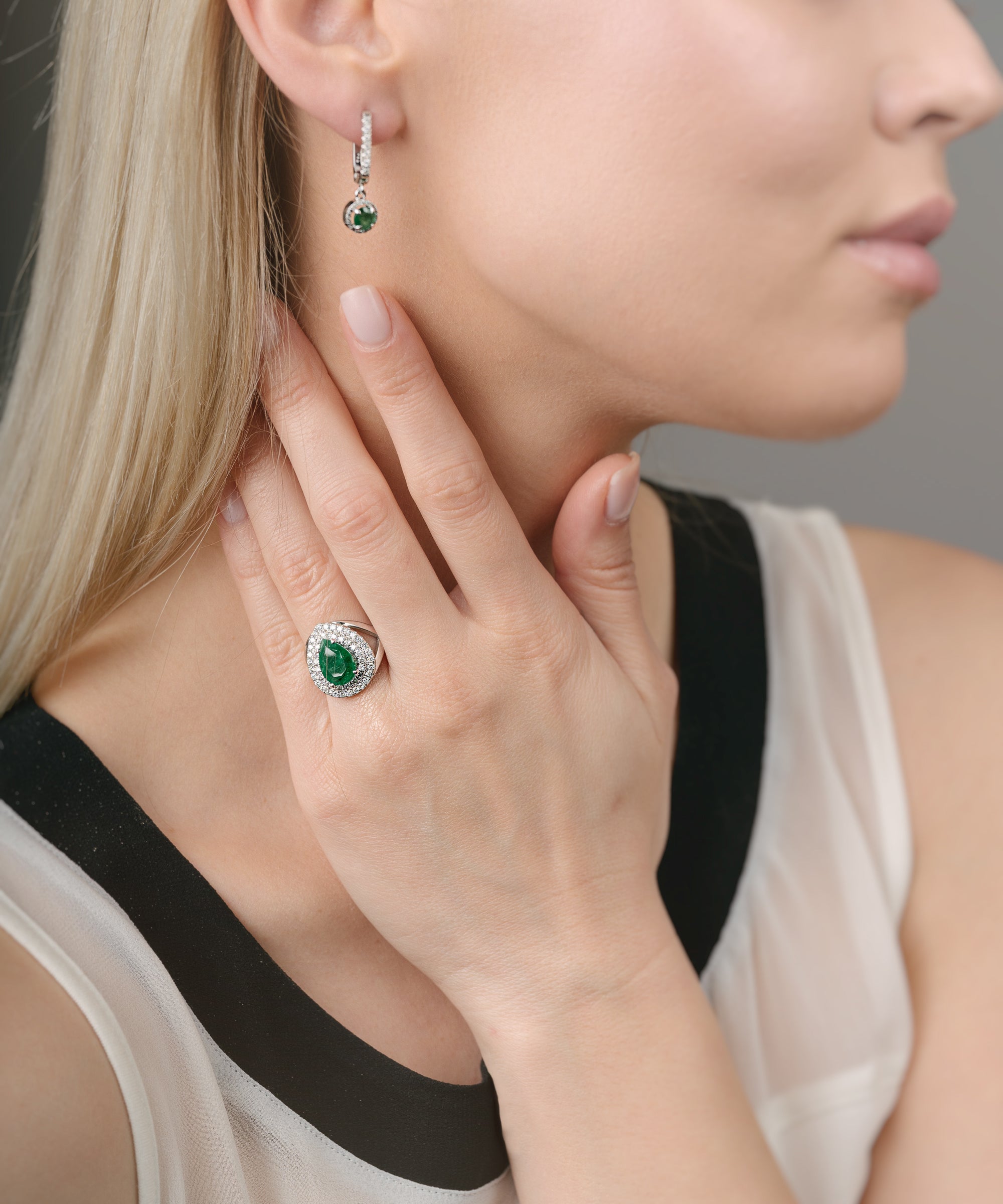 Close-up of a woman wearing emerald green gemstone earrings and ring.