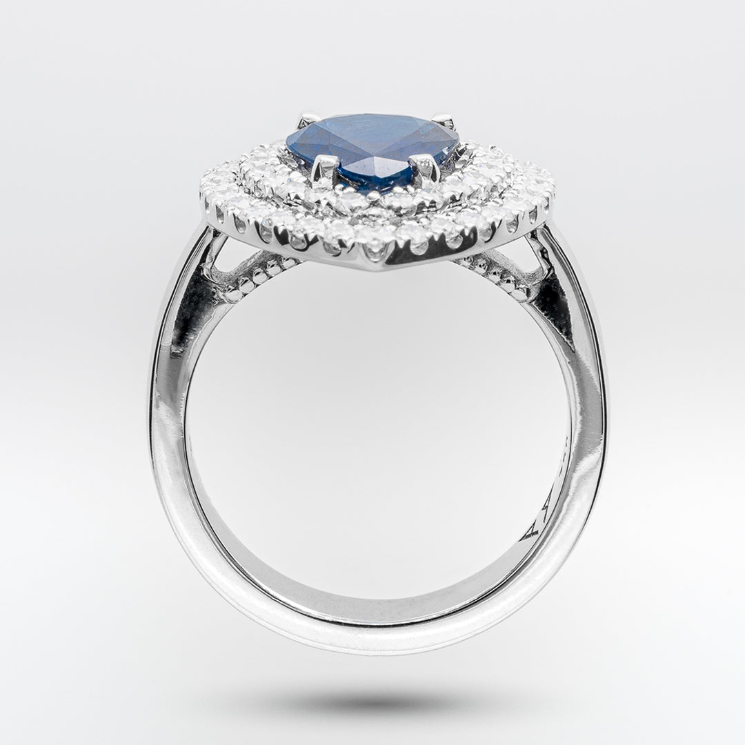 White gold ring with a sapphire gemstone and diamond-studded halo on a light gray background