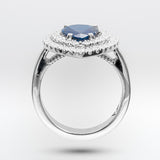 White gold ring with a sapphire gemstone and diamond-studded halo on a light gray background