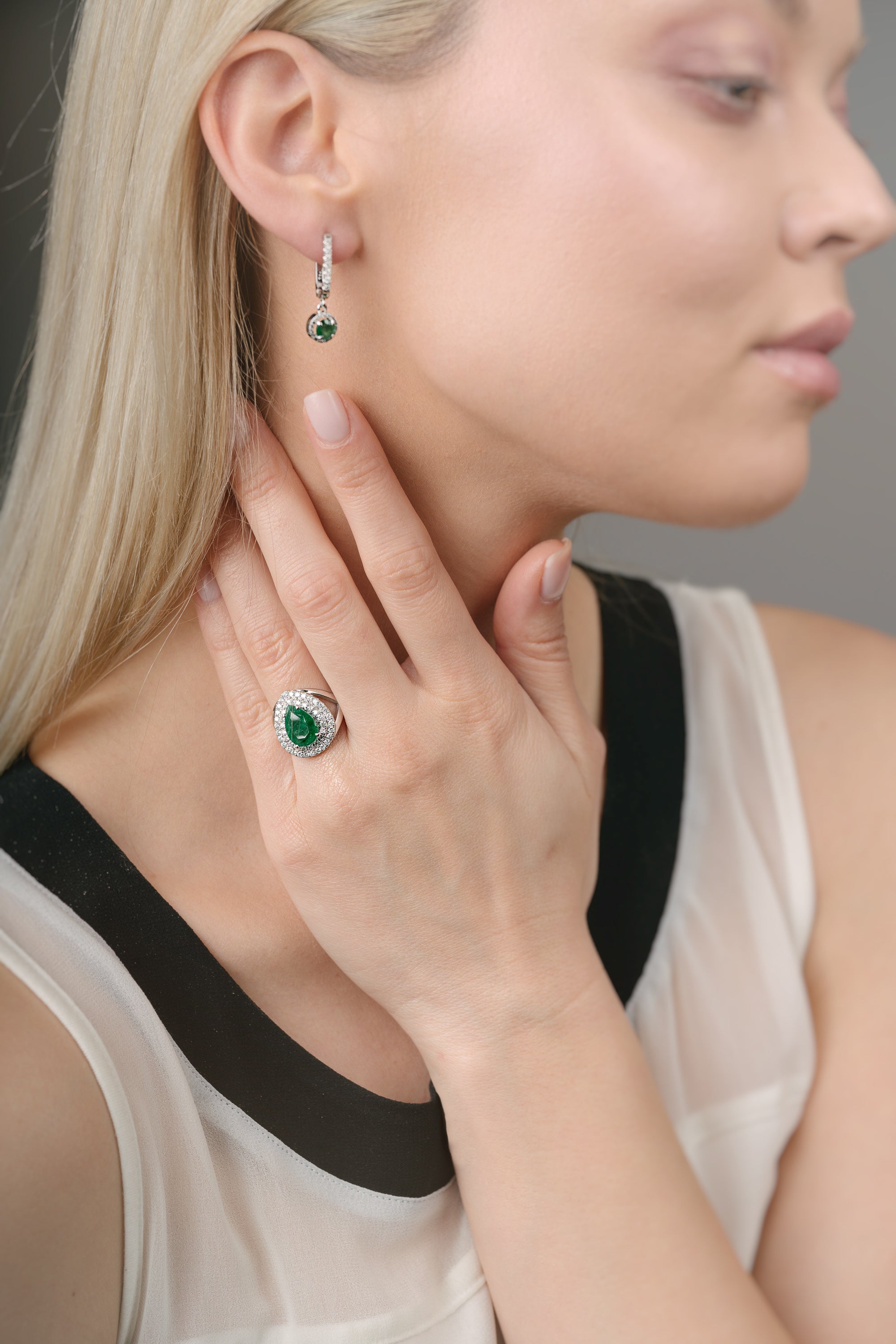 Close-up of a woman wearing emerald green gemstone earrings and ring.