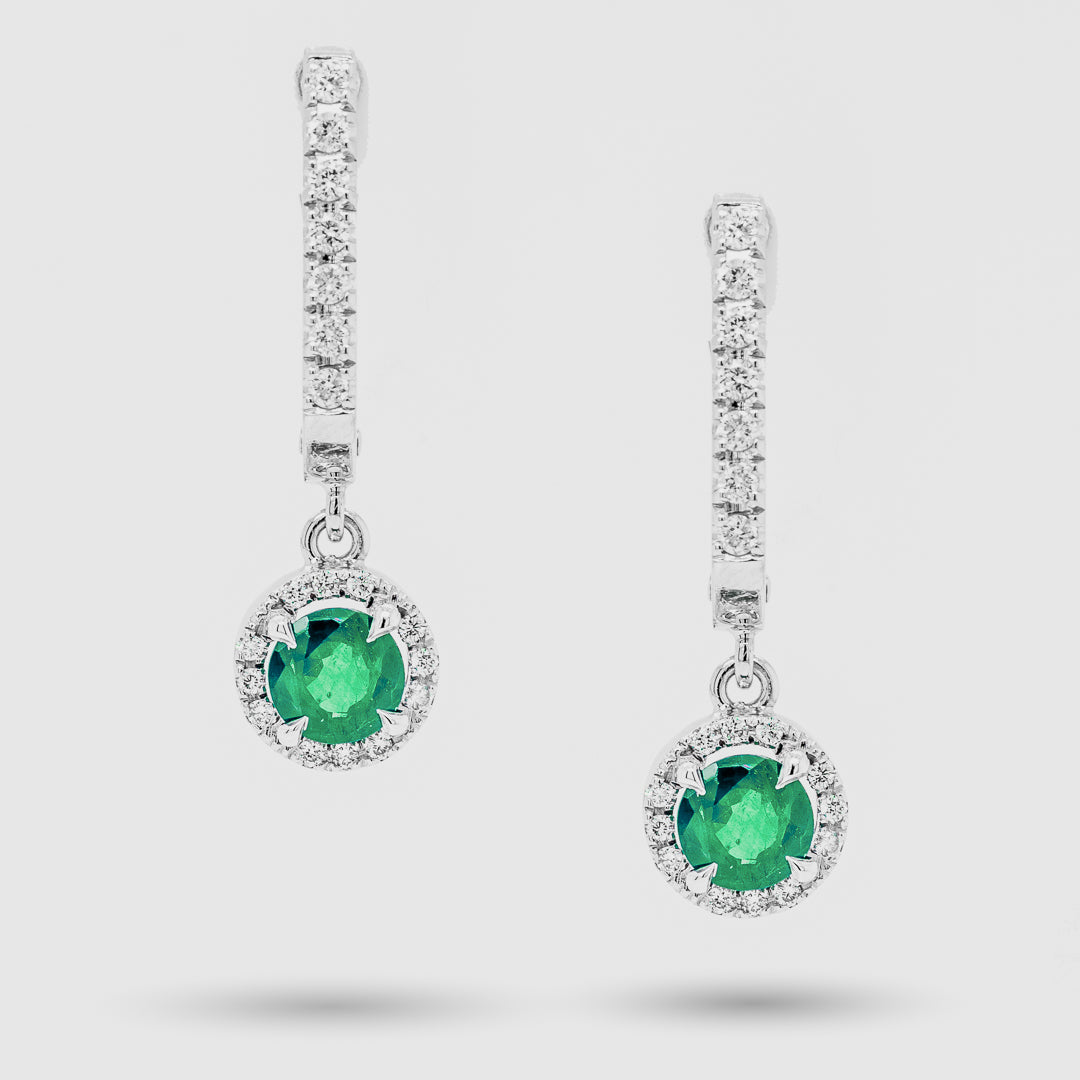 Pair of emerald earrings with diamond accents on a light gray background