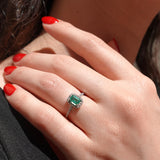 Close-up of a hand wearing an emerald ring with red nail polish.