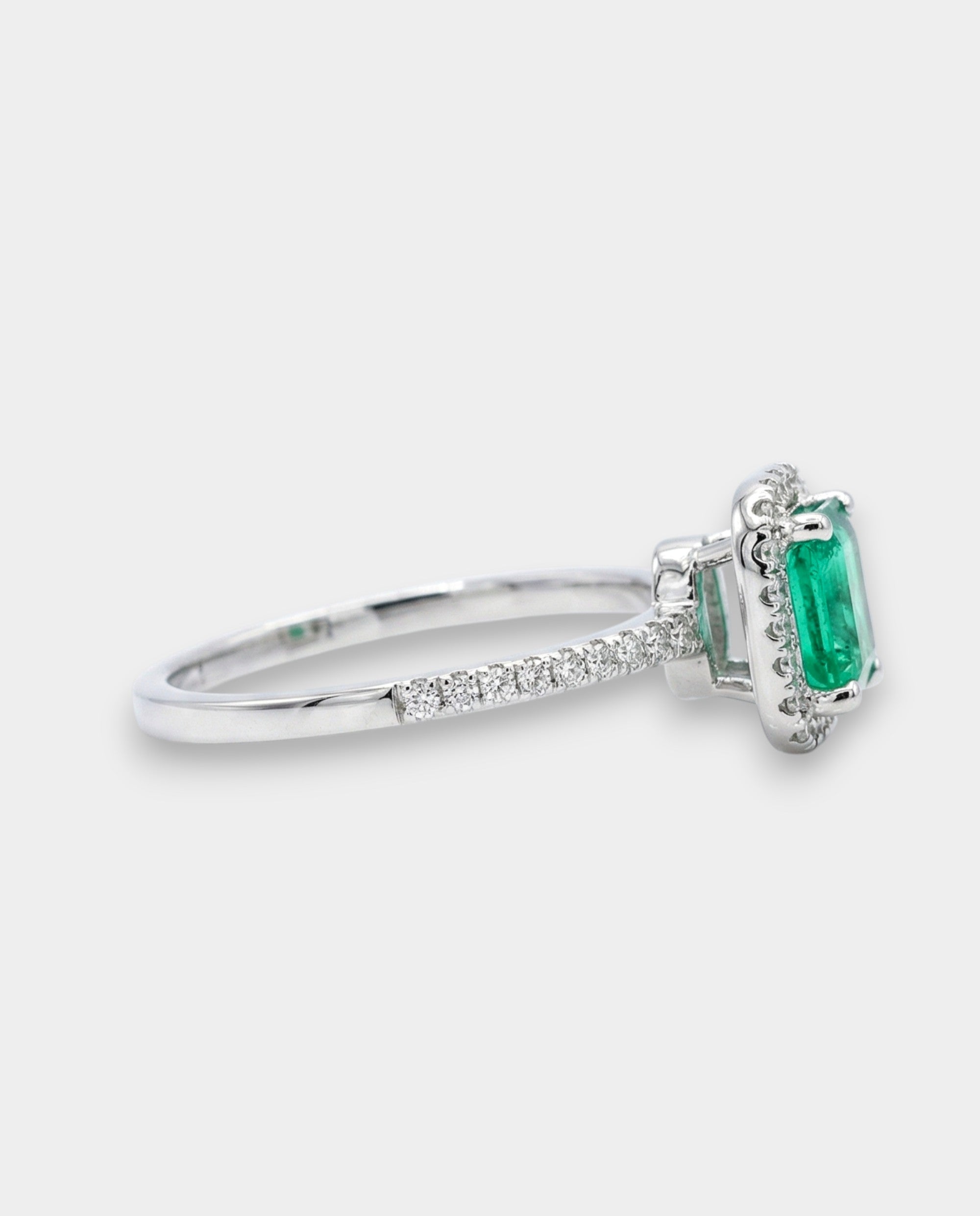 Ring with a green emerald and diamond accents on a white background
