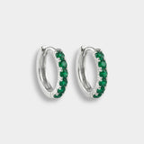 Pair of white gold hoop earrings with emeralds on a white background