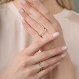 Close-up of a person's hands wearing multiple rings with a neutral background