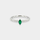 Ring with a green emerald and smaller diamonds on a white background
