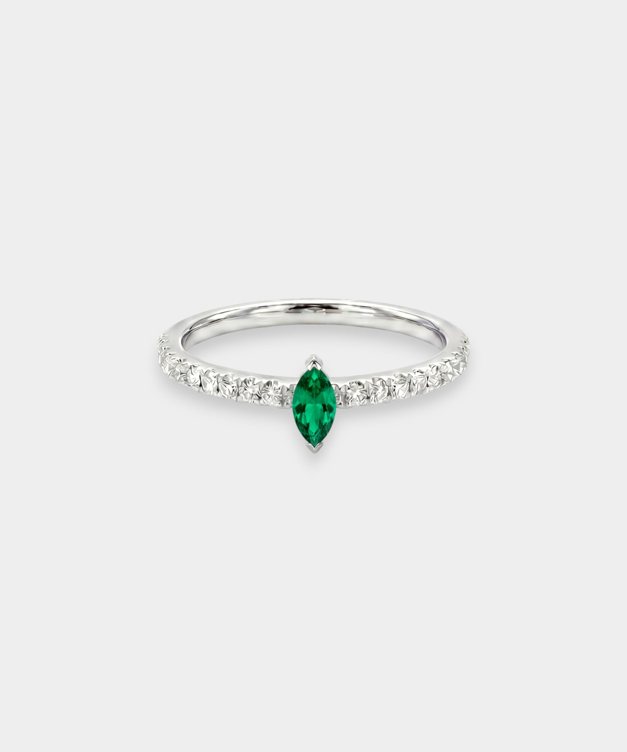 Ring with a green emerald and smaller diamonds on a white background