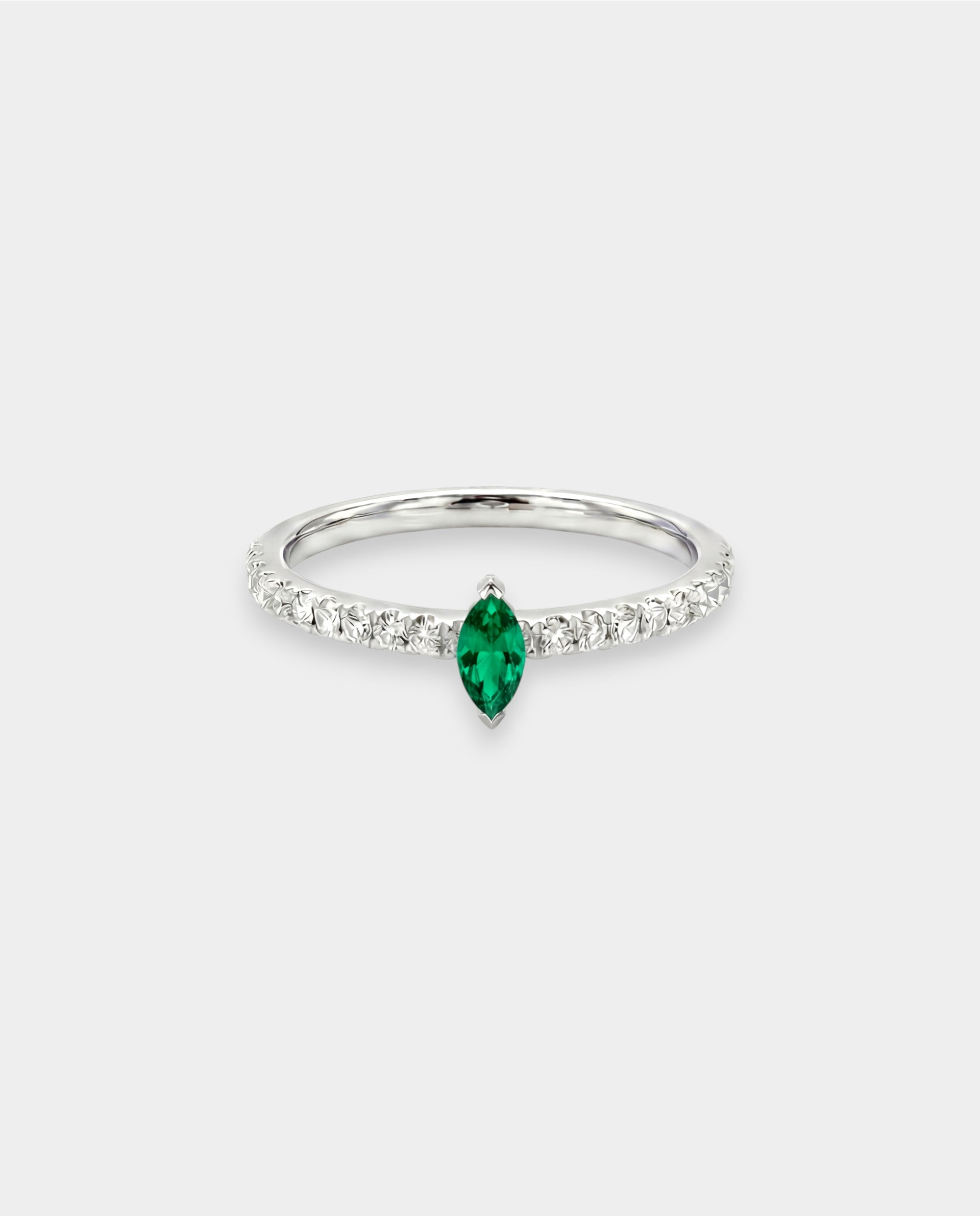 Ring with a green emerald and smaller diamonds on a white background