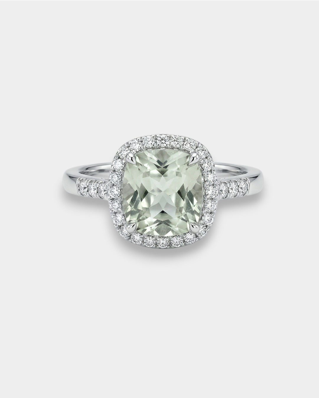 Ring with a green amethyst gemstone and diamond halo on a light gray background